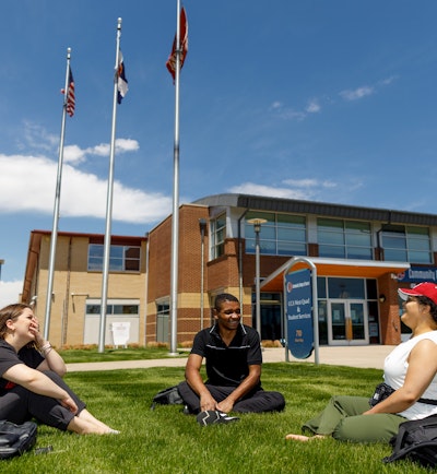 Photo of students sitting on grass in discussion at Community College of Aurora