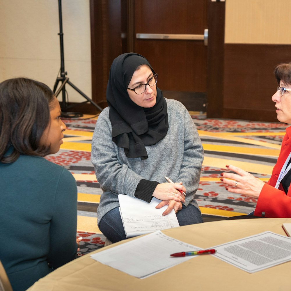 Three women sitting at a table in a conference room during the American Association of Colleges and Universities Annual Meeting. 