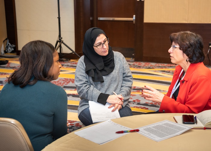 Three women sitting at a table in a conference room during the American Association of Colleges and Universities Annual Meeting.