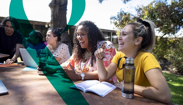 Five students laugh at a picnic table outside while studying